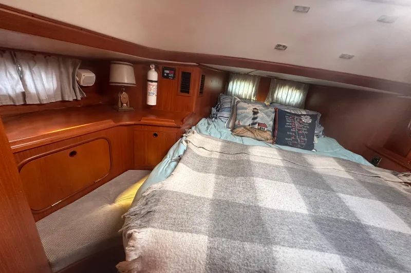 Slide: The Image of Cozy 1991 Taswell Sloop cabin interior with bed, wooden cabinetry, and nautical decor. - 11