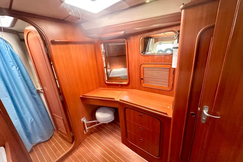 Slide: The Image of Interior of a 1991 Taswell Sloop, featuring elegant wooden cabinetry and a compact workspace. - 17