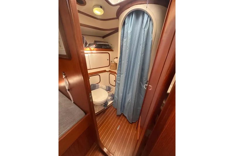 Slide: The Image of 1991 Taswell Sloop bathroom with wooden interior, blue curtain, and compact design. - 22