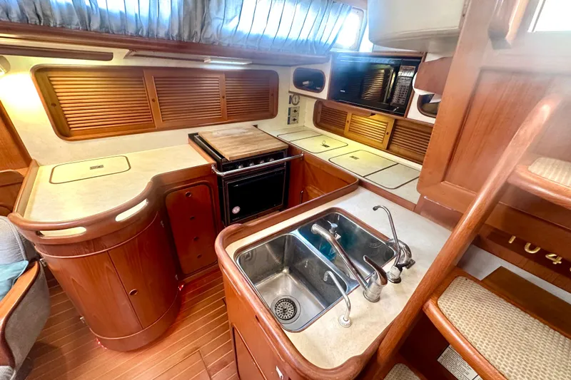 Slide: The Image of Interior of 1991 Taswell Sloop featuring a well-equipped kitchen with wooden cabinetry. - 6
