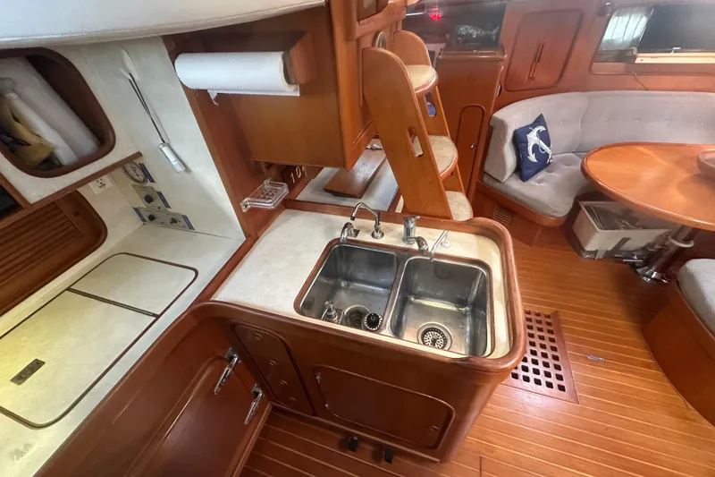 Slide: The Image of 1991 Taswell Sloop interior with kitchen sink, wooden cabinetry, and cozy seating area. - 7
