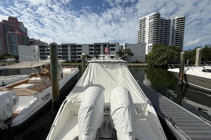 Slide: The Image of 2022 Pursuit S 358 Sport boat docked in a marina with cityscape background. - 10
