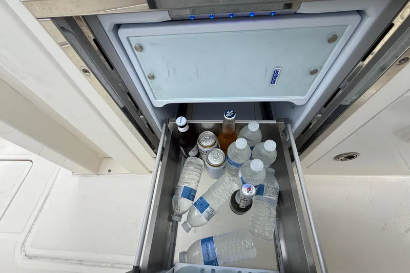 Slide: The Image of Open cooler drawer on 2022 Pursuit S 358 Sport boat with drinks and water bottles. - 115