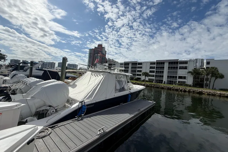 Slide: The Image of 2022 Pursuit S 358 Sport boat docked at marina, under a partly cloudy sky. - 12