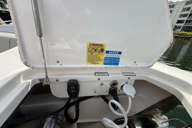 Slide: The Image of 2022 Pursuit S 358 Sport boat utility compartment with warning labels and water connections. - 129