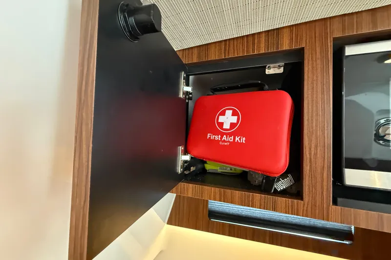 Slide: The Image of Red first aid kit in a wooden cabinet on a 2022 Pursuit S 358 Sport boat. - 143