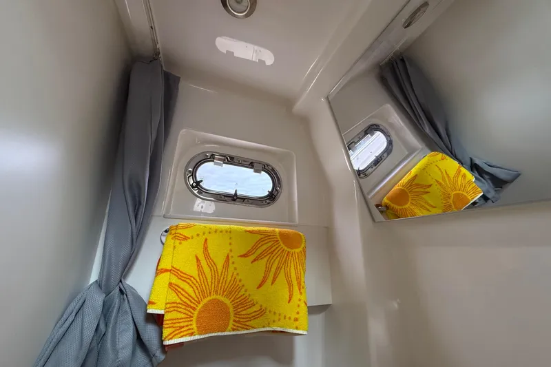 Slide: The Image of Compact bathroom in 2022 Pursuit S 358 Sport boat with porthole and sun-patterned towel. - 146