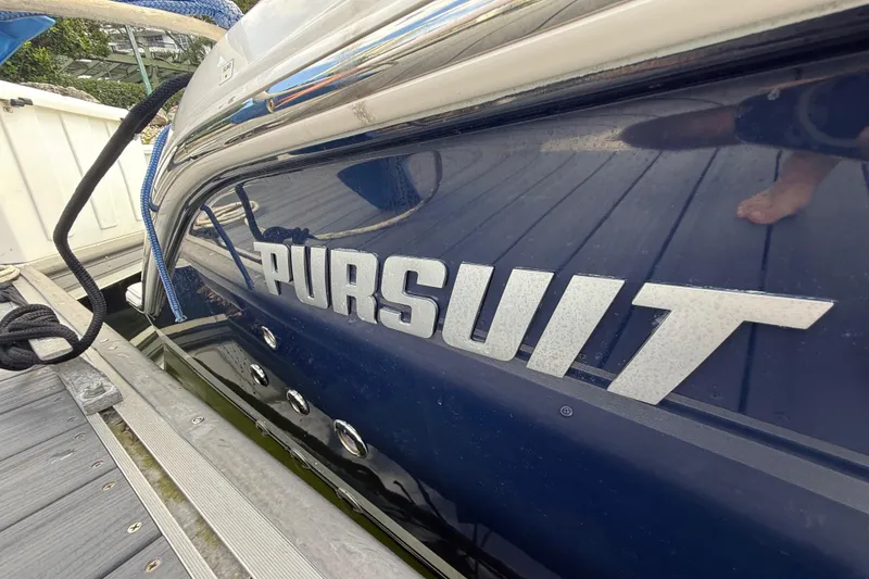 Slide: The Image of 2022 Pursuit S 358 Sport boat docked, showcasing sleek design and branding. - 16