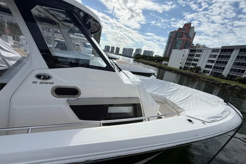 Slide: The Image of 2022 Pursuit S 358 Sport boat docked near waterfront buildings under a cloudy sky. - 17