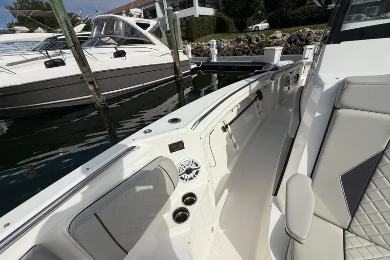 Slide: The Image of 2022 Pursuit S 358 Sport boat interior with seating and speaker, docked beside another boat. - 30