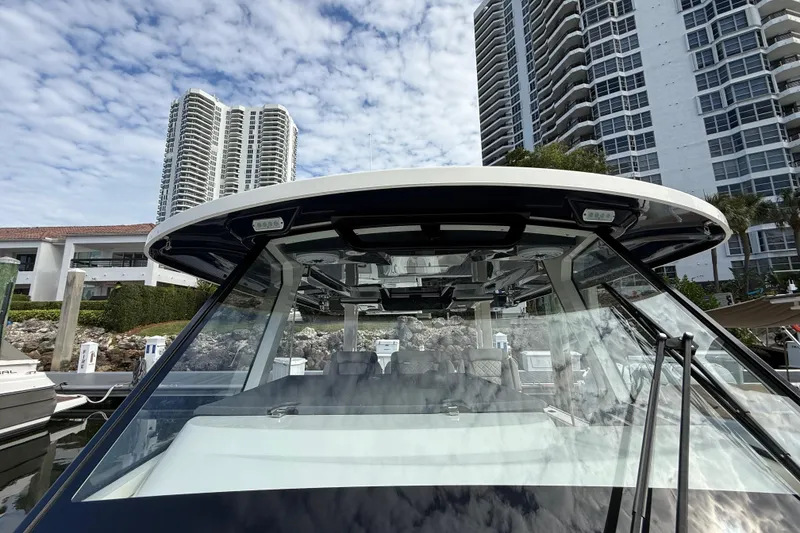 Slide: The Image of 2022 Pursuit S 358 Sport boat docked near high-rise buildings under a cloudy sky. - 42