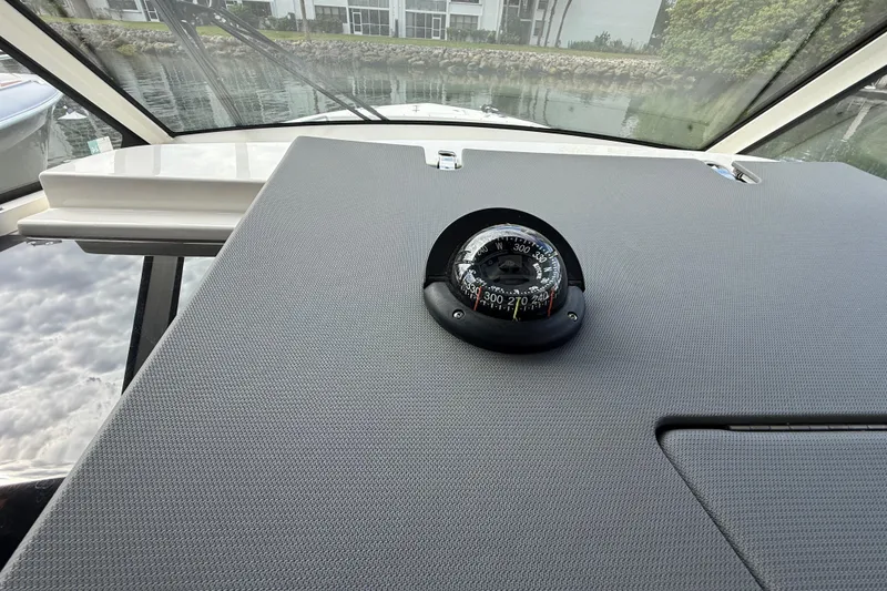 Slide: The Image of Compass on 2022 Pursuit S 358 Sport boat dashboard, with marina view. - 51