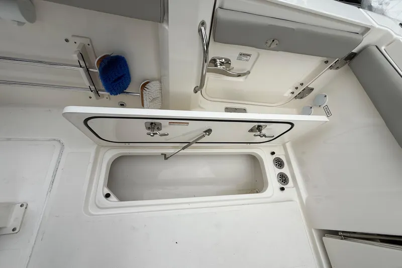 Slide: The Image of 2022 Pursuit S 358 Sport boat storage compartment with cleaning brushes. - 79