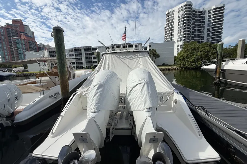 Slide: The Image of 2022 Pursuit S 358 Sport boat docked with covered engines, urban skyline background. - 9