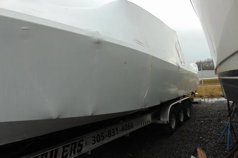 Slide: The Image of 2023 Nor-Tech 390 Sport Center Console boat covered on a trailer. - 2