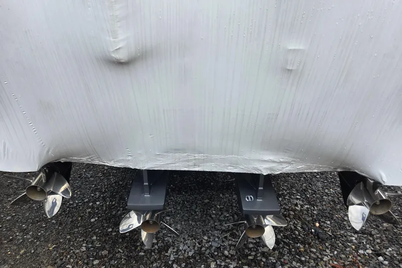 Slide: The Image of 2023 Nor-Tech 390 Sport Center Console boat propellers on gravel surface. - 60