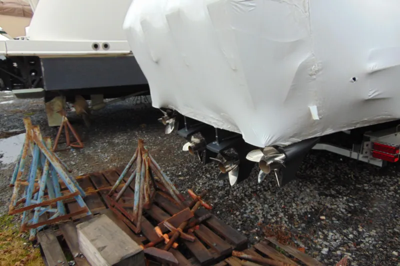 Slide: The Image of 2023 Nor-Tech 390 Sport Center Console boat, covered, with visible propellers and stands nearby. - 8