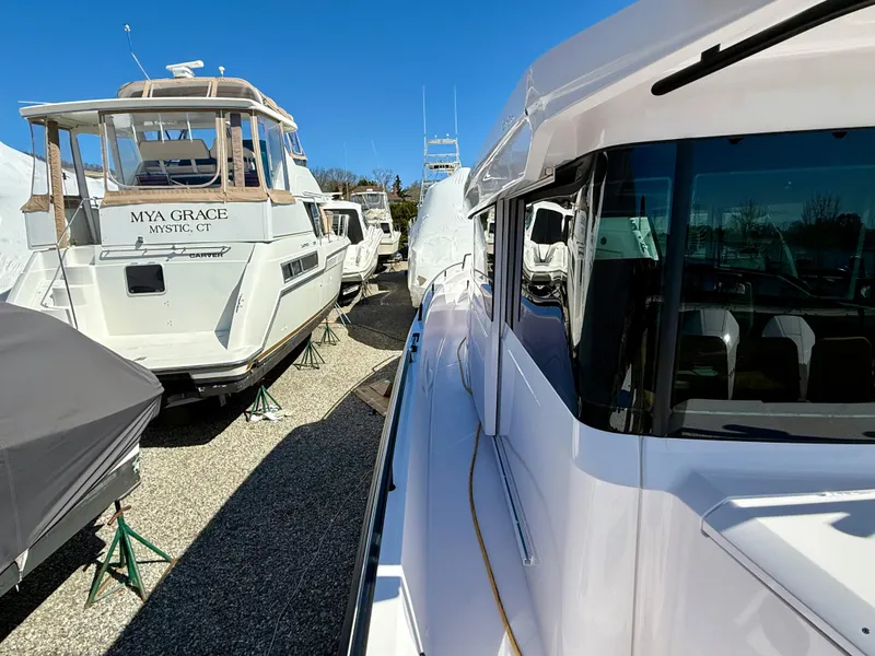 Slide: The Image of 2021 Axopar 37 boat docked alongside other vessels under clear blue sky. - 13