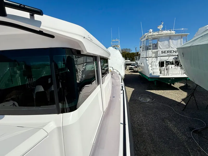 Slide: The Image of Axopar 37 boat, 2021 model, docked alongside other vessels under clear blue sky. - 14