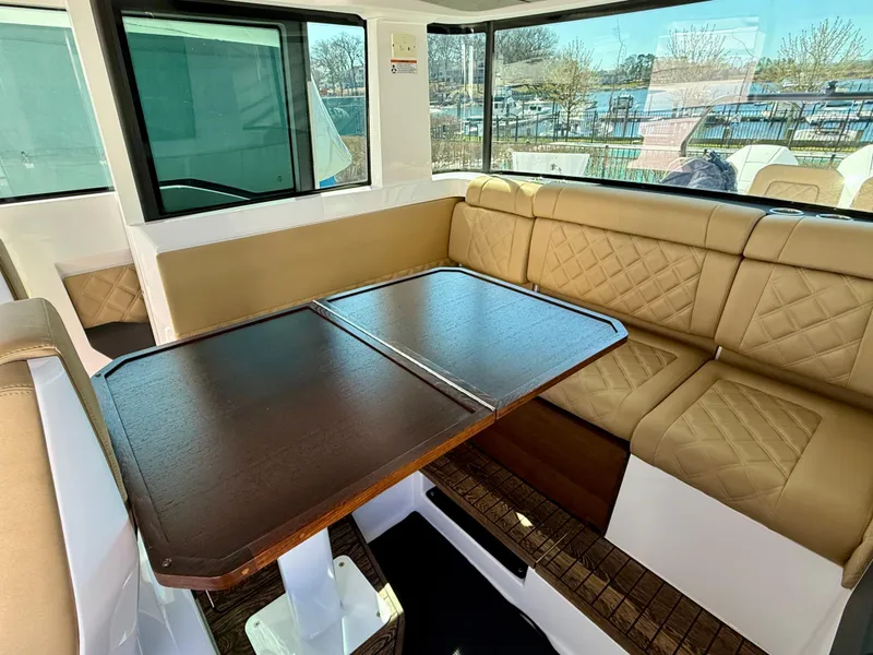 Slide: The Image of Interior of 2021 Axopar 37 boat with tan seating and wooden table. - 20