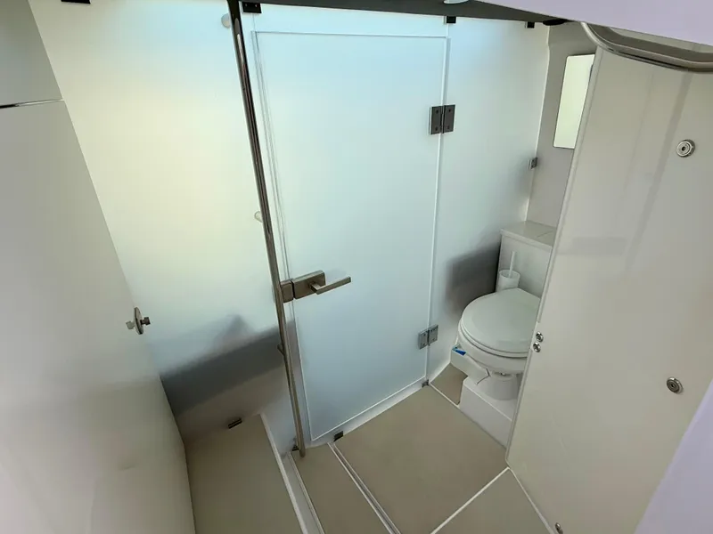 Slide: The Image of Modern bathroom interior on 2021 Axopar 37 boat, featuring a toilet and frosted glass door. - 23