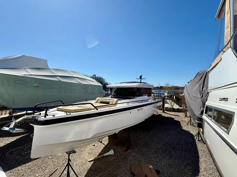 Slide: The Image of 2021 Axopar 37 boat on stands, surrounded by other covered boats in a sunny marina. - 3
