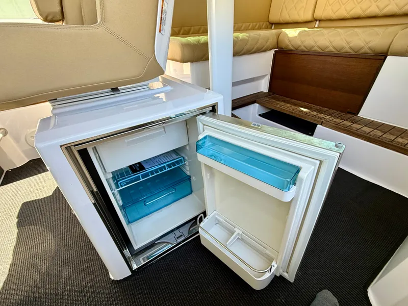 Slide: The Image of 2021 Axopar 37 interior with open mini fridge and beige seating. - 30