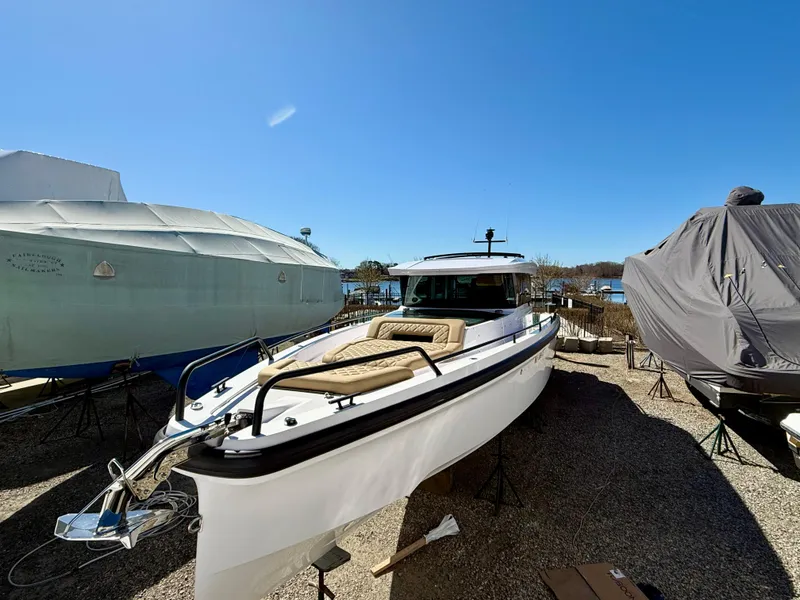 Slide: The Image of 2021 Axopar 37 boat on display, surrounded by covered vessels, under clear blue sky. - 4
