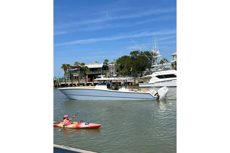 Slide: The Image of 2026 Freeman 47 boat on water near kayaker, dock, and palm trees. - 4