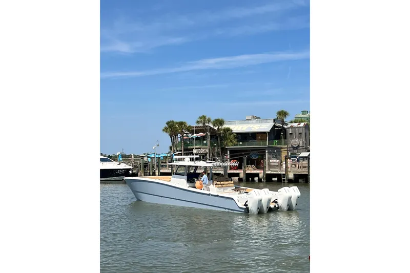 Slide: The Image of 2026 Freeman 47 boat docked near waterfront restaurant, clear blue sky. - 5