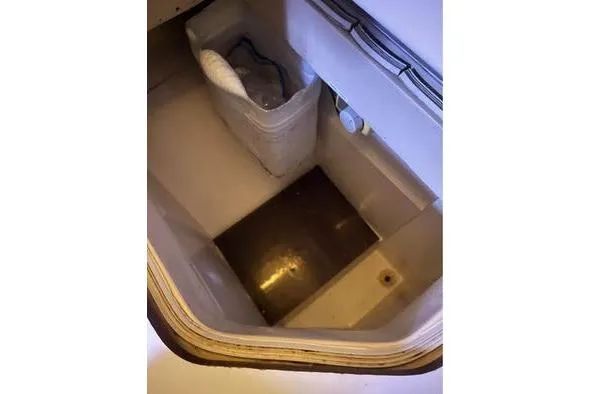 Slide: The Image of Bilge compartment of a 1989 Catalina 42 sailboat, featuring a storage container. - 19