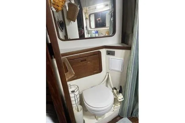 Slide: The Image of 1989 Catalina 42 yacht bathroom with toilet, mirror, and wooden cabinetry. - 20