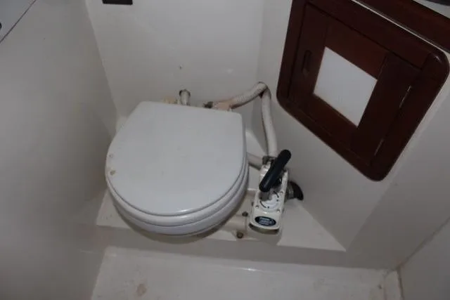 Slide: The Image of 1989 Catalina 42 boat bathroom with manual marine toilet and wooden cabinet. - 34