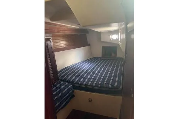 Slide: The Image of 1989 Catalina 42 sailboat cabin with striped bedding and wooden accents. - 37
