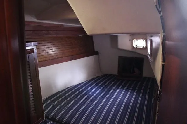 Slide: The Image of Interior cabin of a 1989 Catalina 42 sailboat with striped bedding and wooden accents. - 38