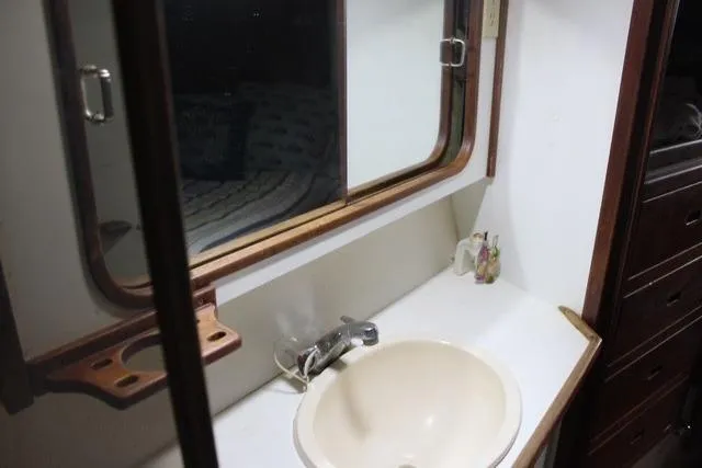 Slide: The Image of Bathroom sink area in a 1989 Catalina 42 yacht, featuring a mirror and wooden accents. - 43