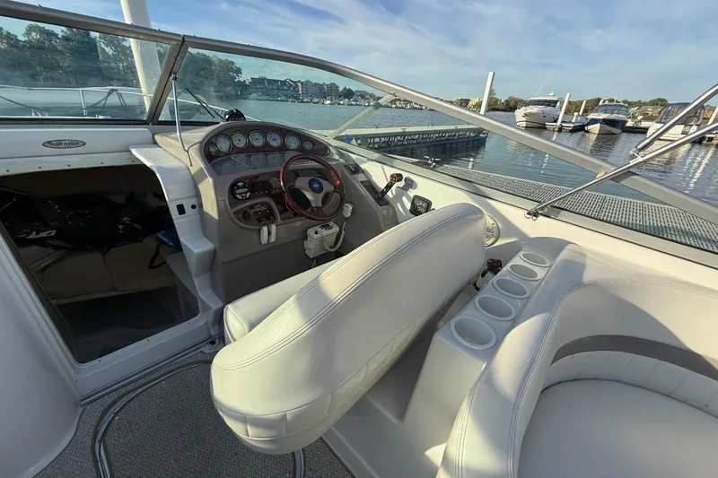 Slide: The Image of 2003 Four Winns 285 Sundowner boat interior with steering wheel and seating, docked by the water. - 4