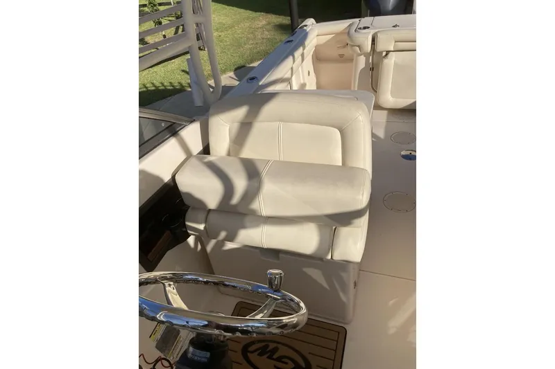 Slide: The Image of 2015 Grady-White Freedom 275 boat interior with white seating and steering wheel. - 17