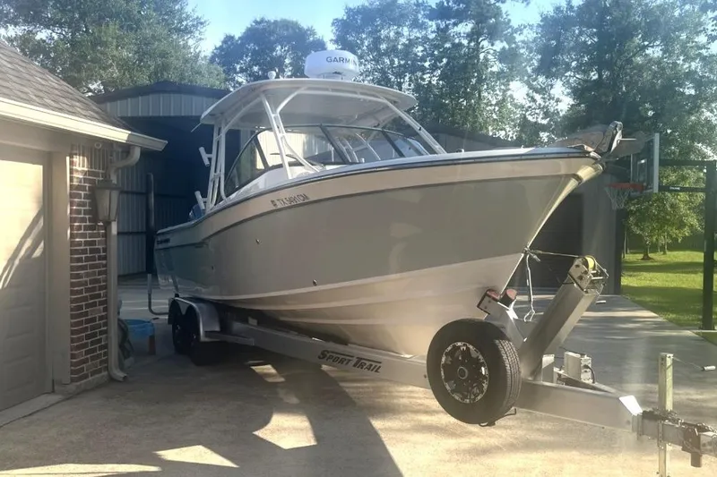 Slide: The Image of 2015 Grady-White Freedom 275 boat on trailer in driveway, surrounded by trees. - 3