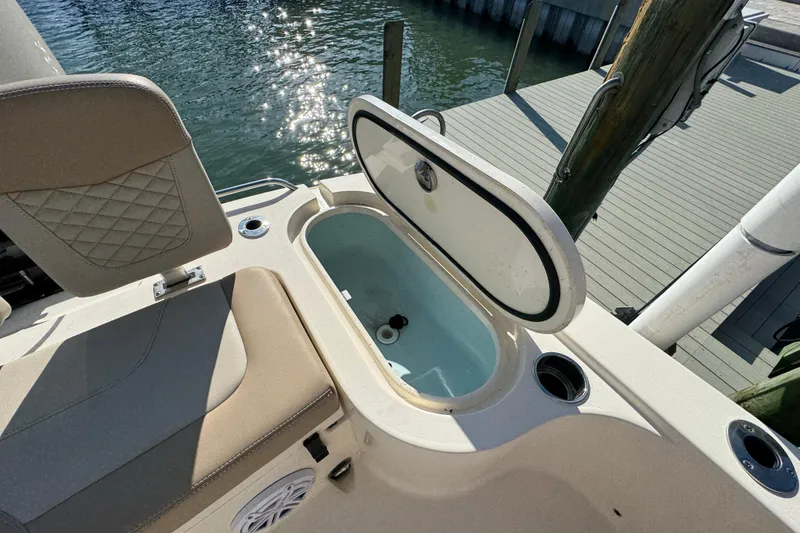 Slide: The Image of 2024 Scout 231 XSB boat with open storage compartment by the water. - 10