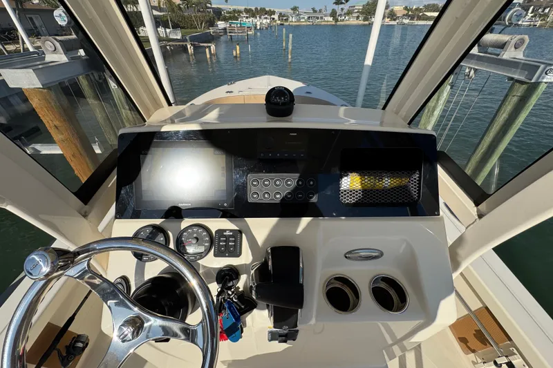 Slide: The Image of 2024 Scout 231 XSB boat dashboard with steering wheel and navigation controls. - 13