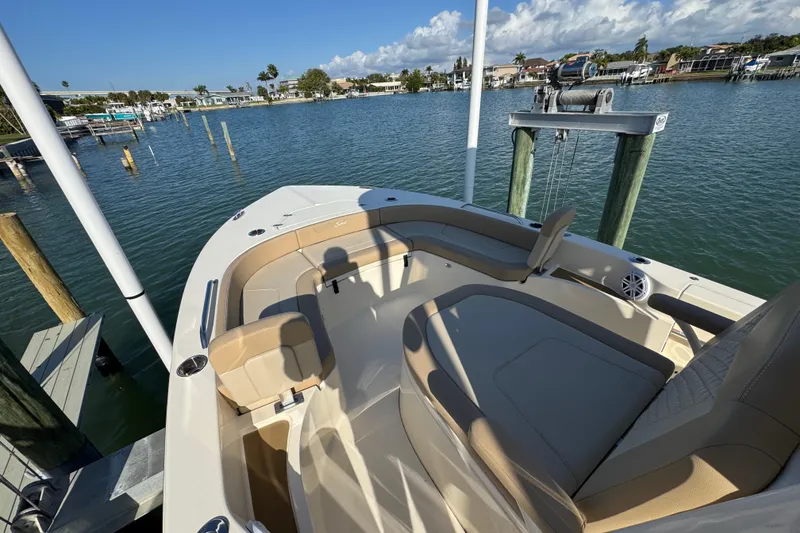 Slide: The Image of 2024 Scout 231 XSB boat interior with tan seating, docked by calm waters. - 15