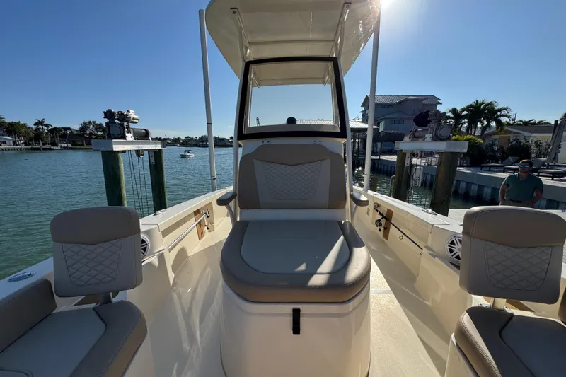 Slide: The Image of 2024 Scout 231 XSB boat interior with seating, docked by waterfront homes. - 19