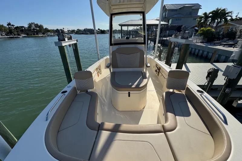 Slide: The Image of 2024 Scout 231 XSB boat interior with seating, docked by waterfront homes. - 20