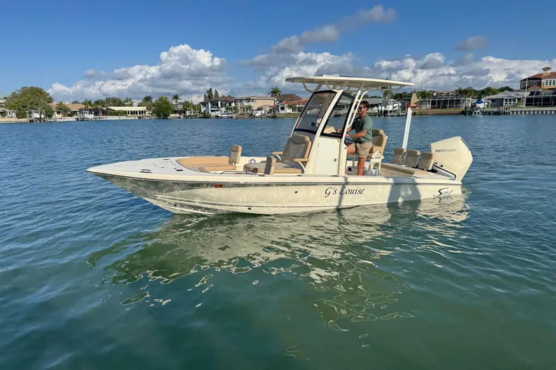 Slide: The Image of 2024 Scout 231 XSB boat on calm water with a person at the helm. - 5