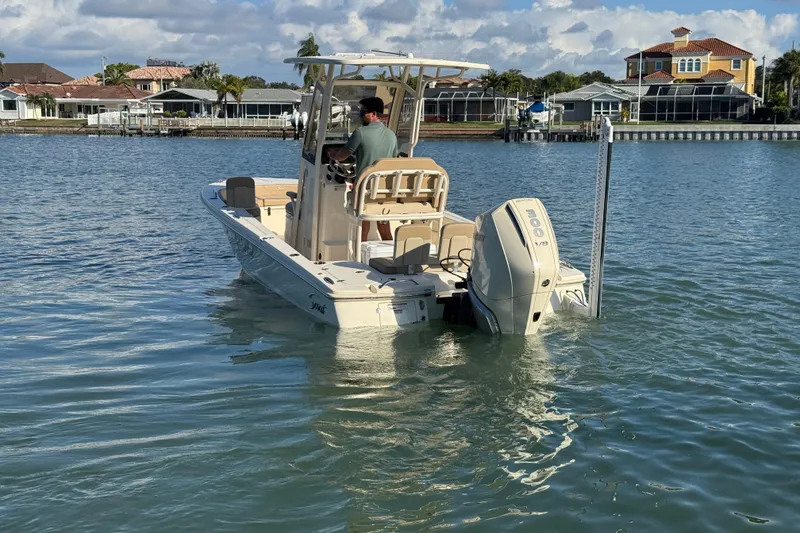 Slide: The Image of 2024 Scout 231 XSB boat on water, with a person at the helm, near waterfront homes. - 6