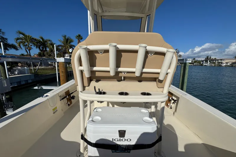 Slide: The Image of 2024 Scout 231 XSB boat interior with rod holders and cooler, docked by the water. - 9