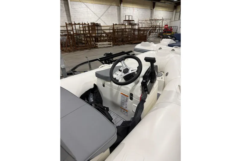 Slide: The Image of 2026 Brig Falcon 330 inflatable boat interior with steering wheel in warehouse setting. - 11