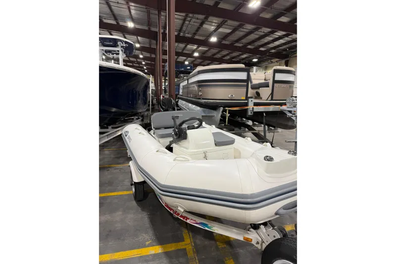 Slide: The Image of 2026 Brig Falcon 330 inflatable boat in a showroom, surrounded by other boats. - 13