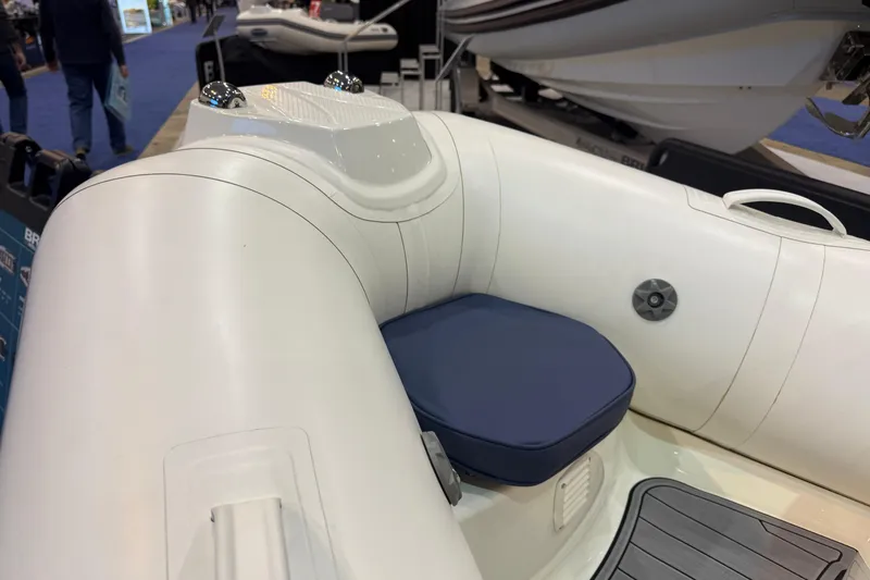 Slide: The Image of 2026 Brig Falcon 330 inflatable boat interior with blue seat cushion at a boat show. - 14